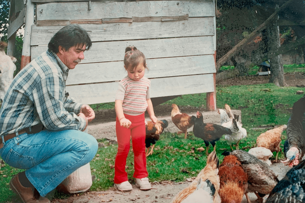 Man and girl feed chickens on a farm, a scene from Ecuador.
