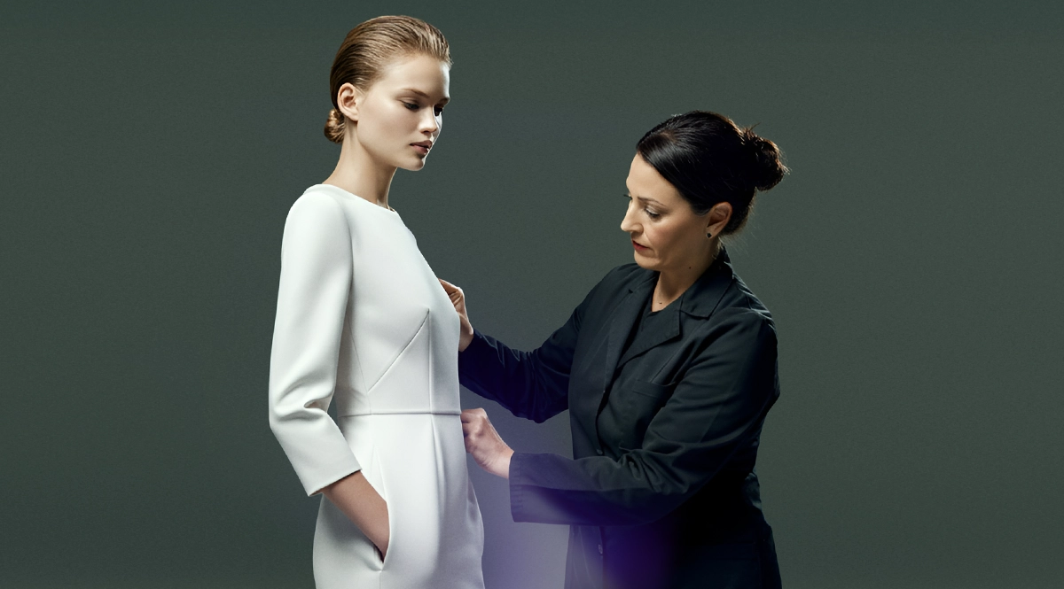 CEO's perspective: Dressmaker fitting a model for a white dress.