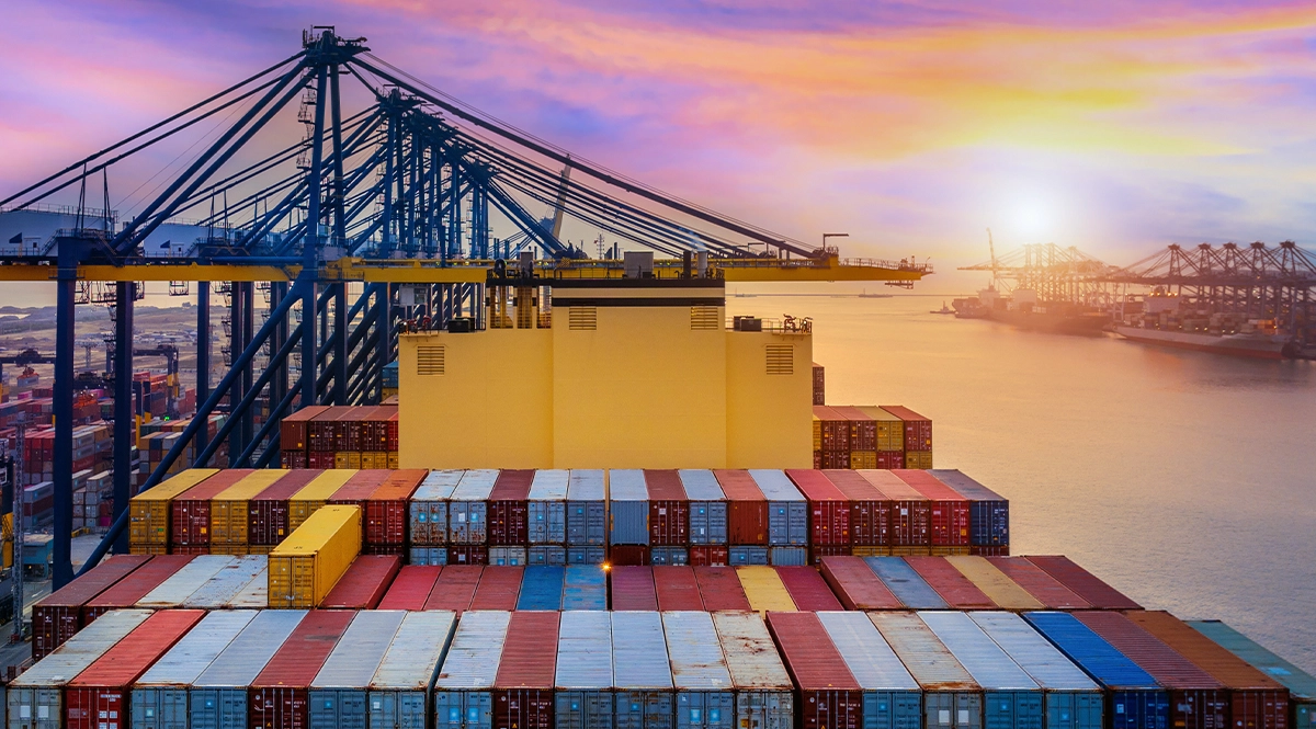 Container ship at port with cranes, symbolizing fashion supply chains in 2026.